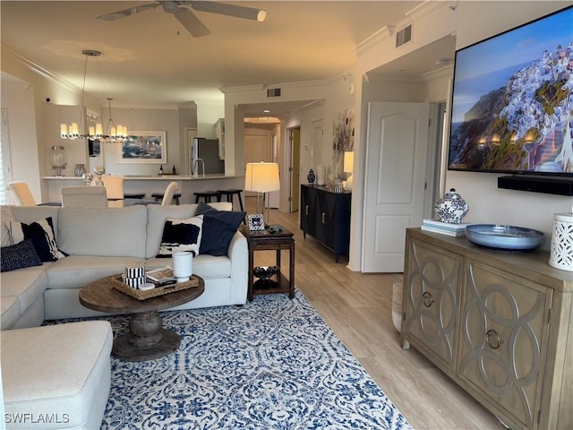 living room featuring ceiling fan with notable chandelier, crown molding, and light wood-type flooring