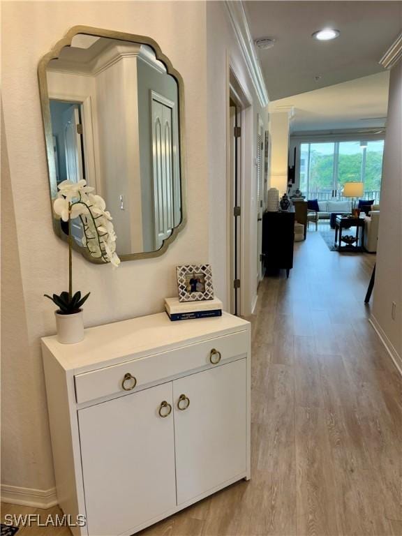 hallway with light hardwood / wood-style flooring and ornamental molding