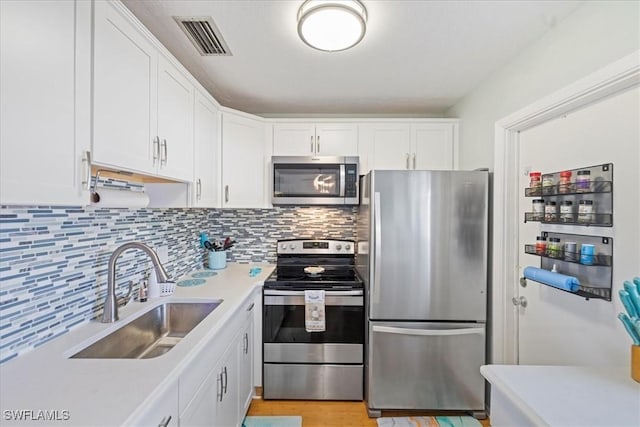 kitchen with backsplash, sink, white cabinetry, and appliances with stainless steel finishes