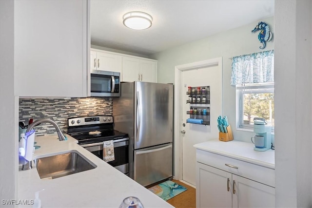 kitchen featuring white cabinets, decorative backsplash, appliances with stainless steel finishes, and sink