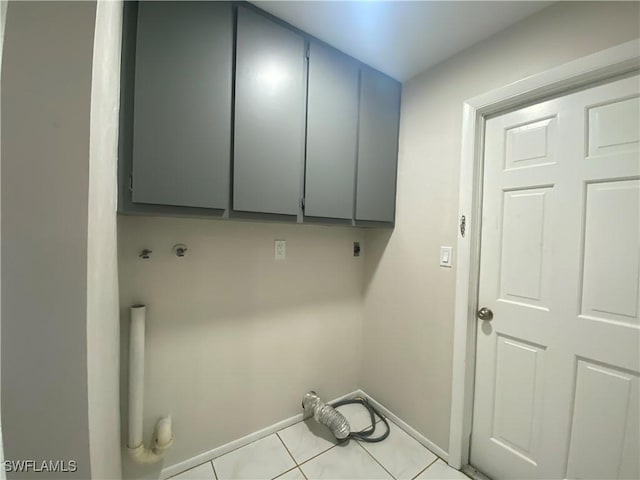 laundry area with light tile patterned flooring, cabinets, and hookup for an electric dryer