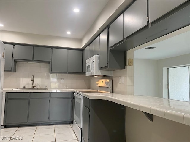 kitchen with white appliances, tile countertops, sink, and gray cabinetry