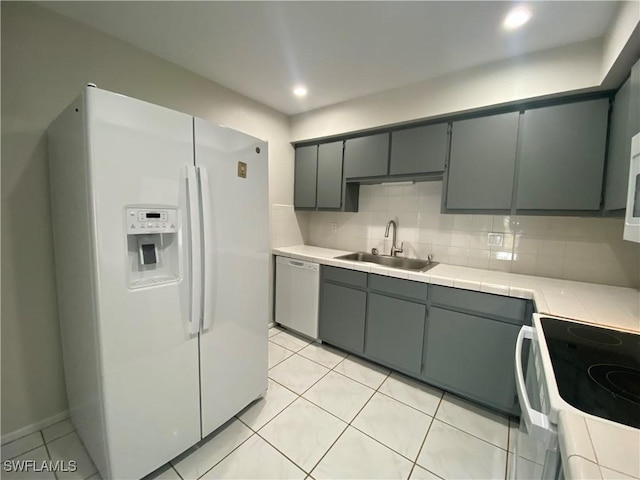 kitchen featuring light tile patterned flooring, sink, tile counters, white appliances, and backsplash