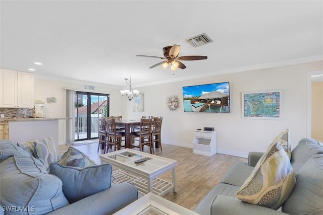 living room with ceiling fan with notable chandelier, sink, light hardwood / wood-style flooring, and ornamental molding