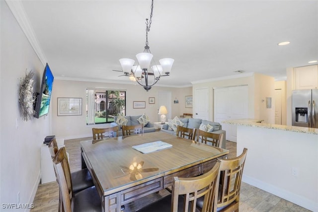 dining space with a notable chandelier, ornamental molding, and light hardwood / wood-style flooring