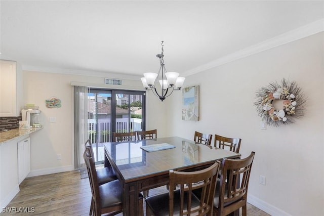 dining space featuring light hardwood / wood-style floors, crown molding, and a chandelier