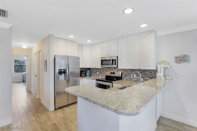 kitchen featuring kitchen peninsula, sink, white cabinetry, light stone countertops, and appliances with stainless steel finishes