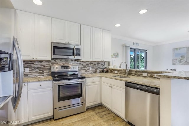 kitchen featuring white cabinetry, kitchen peninsula, stainless steel appliances, light stone counters, and sink