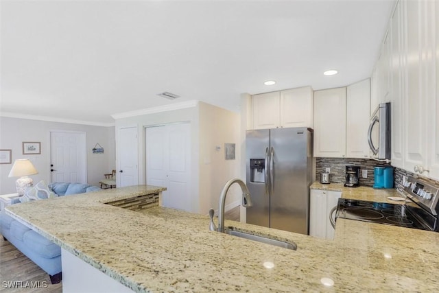 kitchen featuring appliances with stainless steel finishes, white cabinetry, sink, kitchen peninsula, and light stone counters