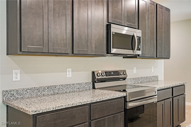 kitchen featuring light stone countertops, stainless steel appliances, and dark brown cabinets