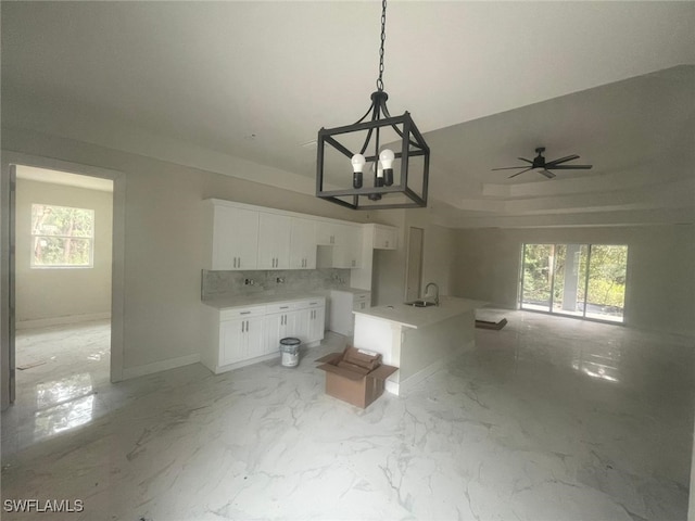 kitchen with plenty of natural light, white cabinetry, tasteful backsplash, and sink