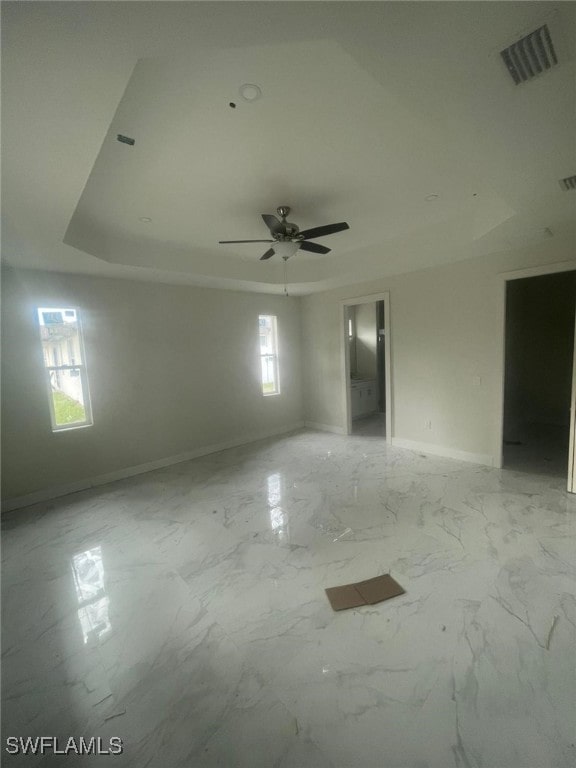 spare room with ceiling fan and a raised ceiling