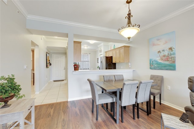 dining area with crown molding and light hardwood / wood-style flooring