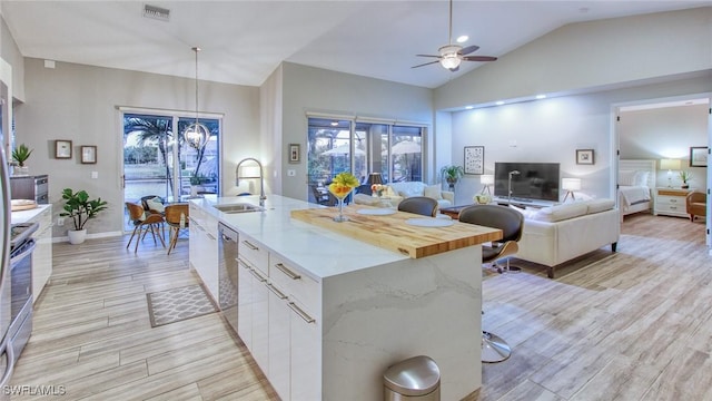 kitchen featuring white cabinetry, appliances with stainless steel finishes, a kitchen island with sink, hanging light fixtures, and sink