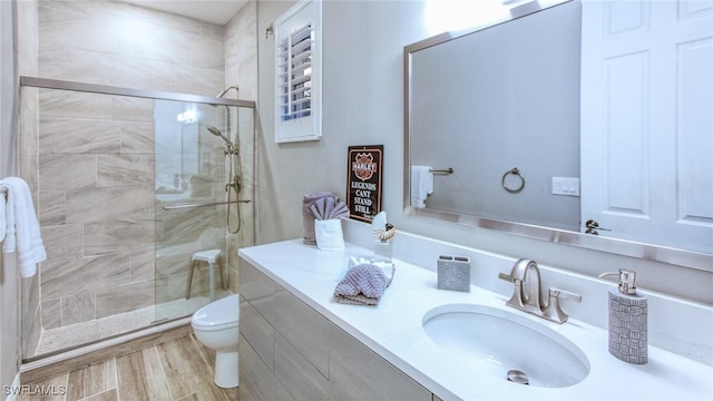 bathroom with wood-type flooring, toilet, a shower with door, and vanity