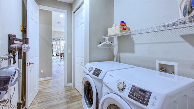 clothes washing area with washer and clothes dryer and light hardwood / wood-style flooring