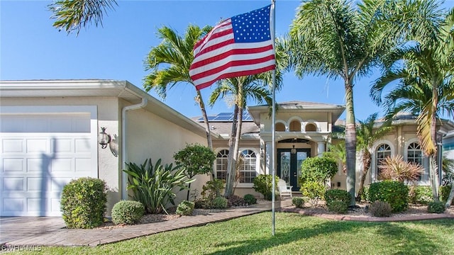 view of front of home with a front yard, french doors, solar panels, and a garage