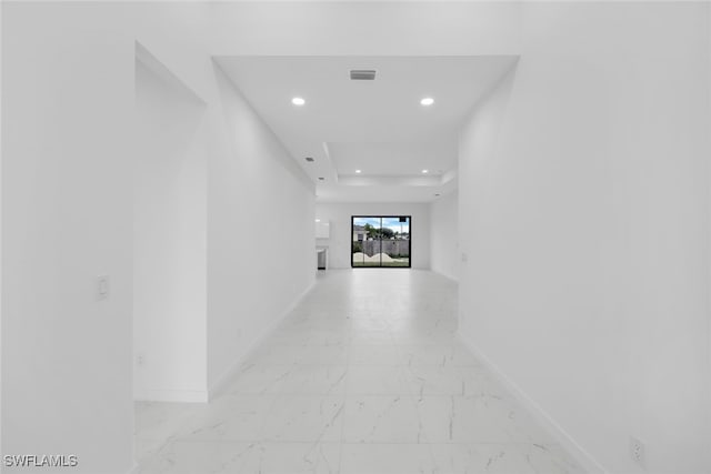 corridor with recessed lighting, visible vents, baseboards, marble finish floor, and a tray ceiling