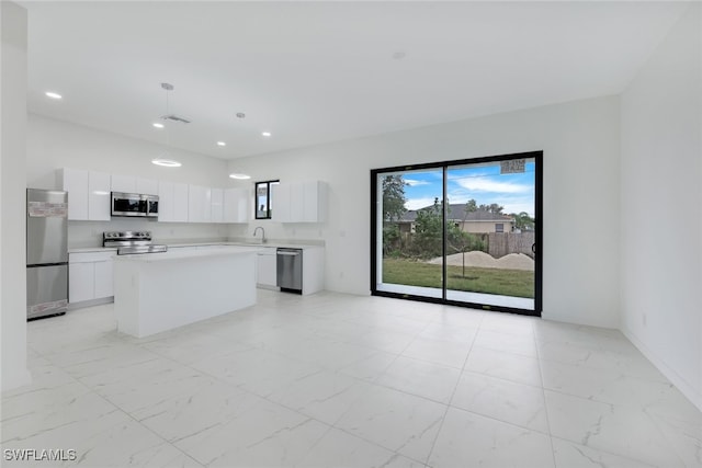 kitchen with white cabinets, appliances with stainless steel finishes, a center island, marble finish floor, and light countertops