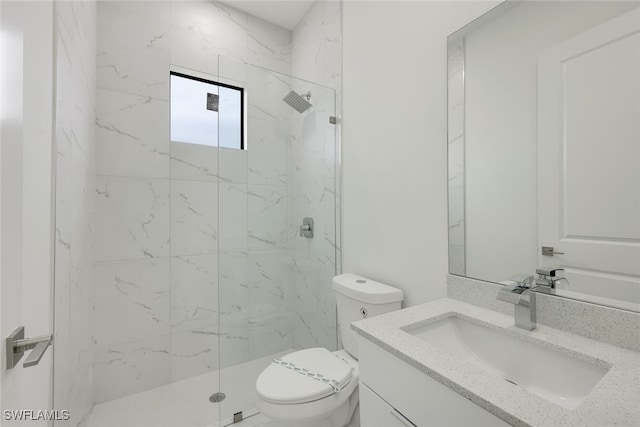 bathroom featuring toilet, a marble finish shower, and vanity