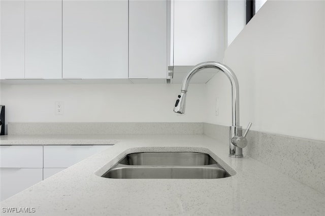 details with light stone counters, white cabinets, a sink, and modern cabinets