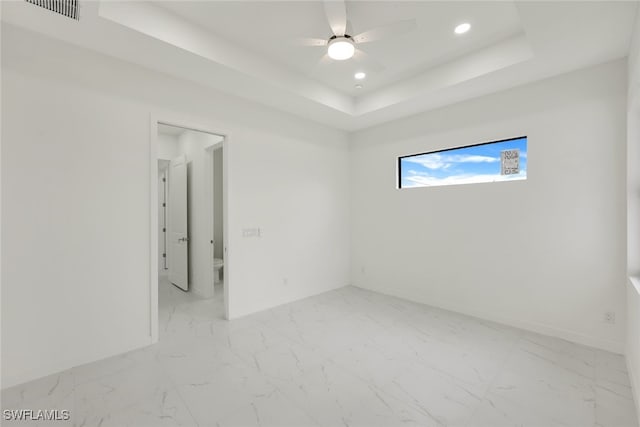 empty room featuring marble finish floor, a raised ceiling, and recessed lighting