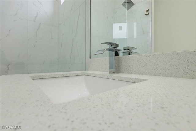 bathroom with vanity and a marble finish shower