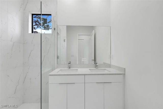 bathroom featuring a sink, a marble finish shower, and double vanity