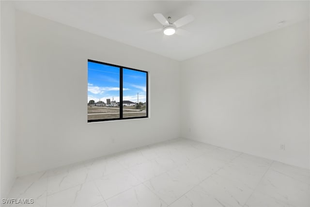 empty room featuring ceiling fan and marble finish floor