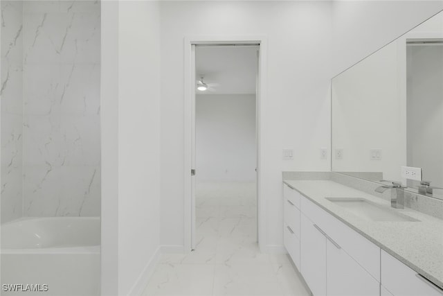 full bathroom with marble finish floor, baseboards, a tub, and vanity