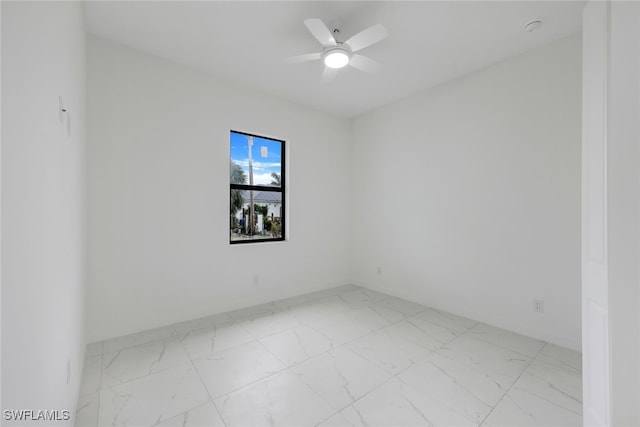 spare room featuring a ceiling fan and marble finish floor