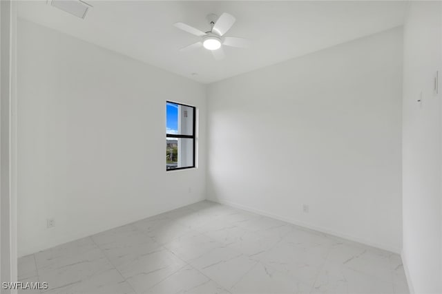 spare room with marble finish floor, baseboards, and a ceiling fan