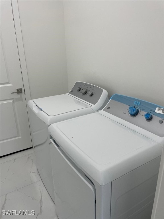 laundry room featuring marble finish floor, laundry area, and washing machine and clothes dryer