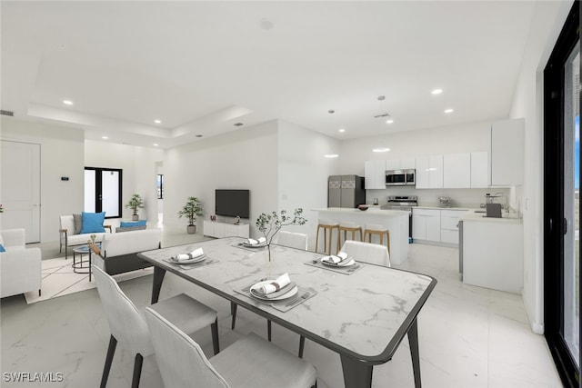 dining room featuring marble finish floor, a raised ceiling, and recessed lighting