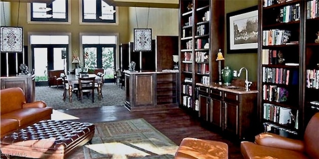 living room featuring a towering ceiling, dark hardwood / wood-style floors, built in features, and french doors