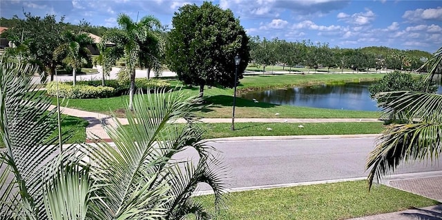 surrounding community with a water view and a lawn