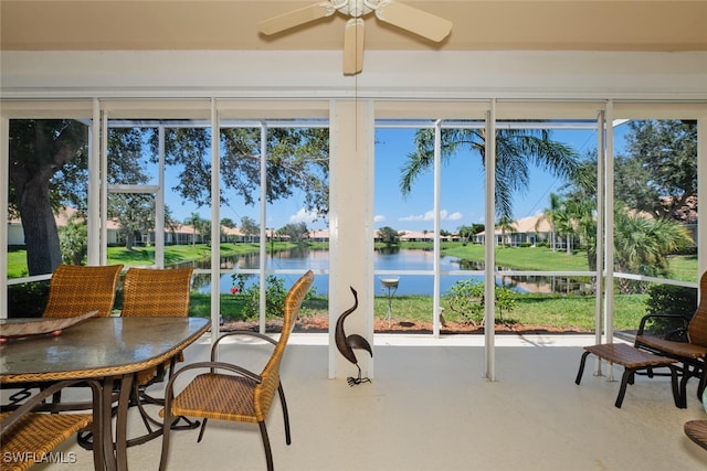 sunroom with ceiling fan and a water view