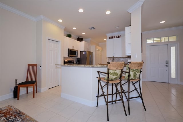 kitchen featuring appliances with stainless steel finishes, white cabinetry, backsplash, kitchen peninsula, and light stone counters