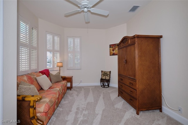 living area with ceiling fan, a wealth of natural light, and light colored carpet