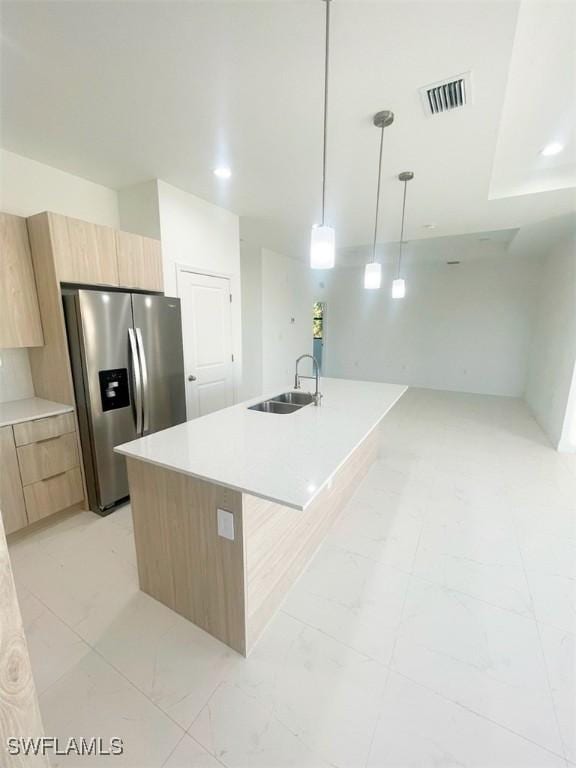 kitchen featuring visible vents, stainless steel fridge with ice dispenser, modern cabinets, light brown cabinetry, and a sink