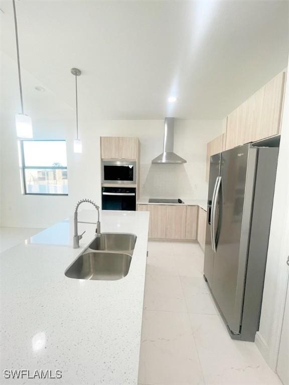 kitchen featuring light brown cabinetry, appliances with stainless steel finishes, a sink, wall chimney range hood, and modern cabinets