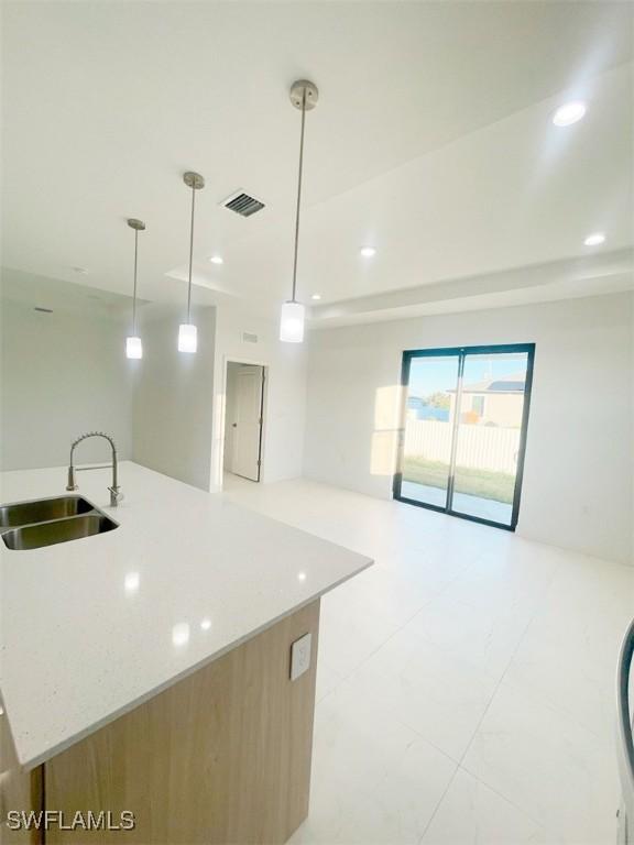 kitchen featuring visible vents, open floor plan, a sink, and recessed lighting