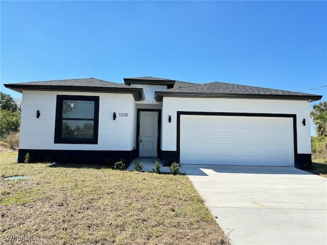 view of front facade featuring a garage, a front yard, concrete driveway, and stucco siding