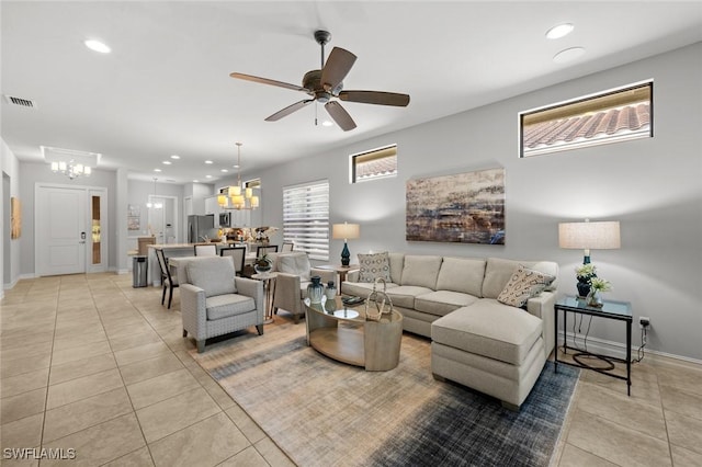 tiled living room with ceiling fan with notable chandelier