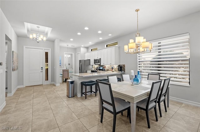 dining space featuring a raised ceiling, a notable chandelier, and light tile patterned flooring