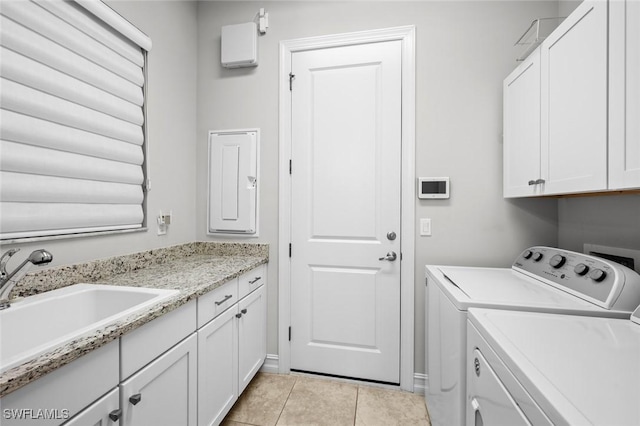 washroom with sink, light tile patterned flooring, washer and dryer, and cabinets