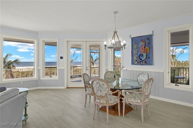 dining space featuring a wealth of natural light, a water view, french doors, and a notable chandelier