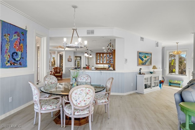 dining space featuring light wood-type flooring, a chandelier, and crown molding