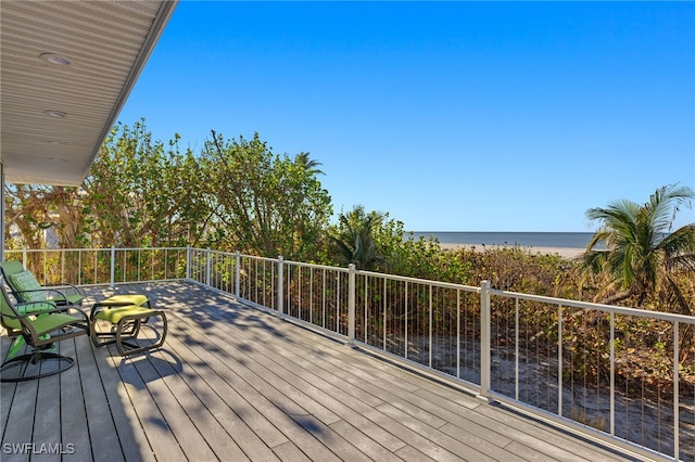 wooden deck featuring a water view and a beach view