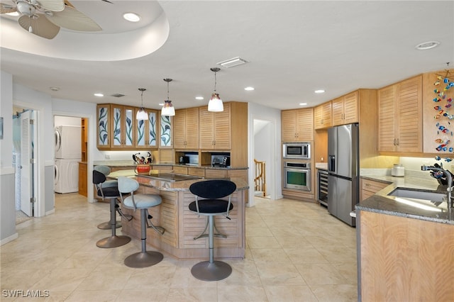 kitchen with light stone countertops, appliances with stainless steel finishes, a center island, and sink